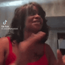 a woman in a red tank top is making a funny face with her hands .