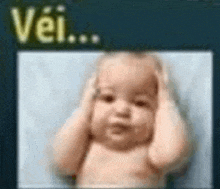 a baby is covering his ears with his hands in front of a sign that says vei ...