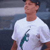 a man wearing a black hat and a white t-shirt with a tennis player on it