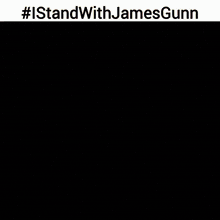 a man in a suit is standing in front of a fire with #istandwithjamesgunn