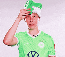 a man wearing a green shirt and a green hat with the letter w on it