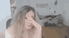 a woman is covering her face with her hand .