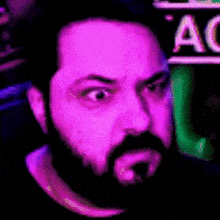 a man with a beard is looking at the camera with a purple background