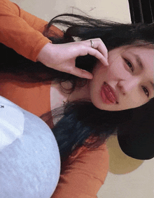 a woman wearing an orange shirt and a black hat is taking a picture of herself