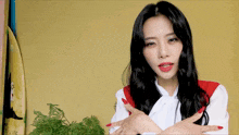 a woman with red nails and a white shirt has her arms crossed in front of a surfboard