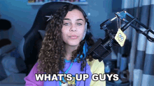 a woman in front of a microphone with the words what 's up guys written below her