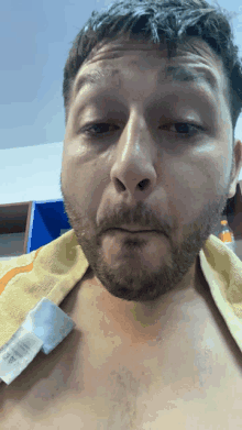 a shirtless man with a yellow towel around his neck has a tag on his chest that says ' calvin klein ' on it