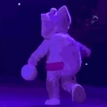 a purple teddy bear is dancing in the dark