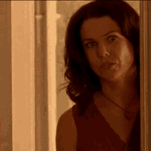 a woman in a red top is looking out a doorway
