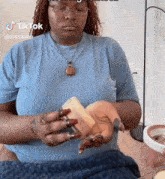 a woman wearing glasses and a blue shirt is holding a piece of soap in her hands .