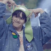 a person wearing a green beanie and a denim jacket with a patch that says hq on it