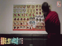 a man in a red jacket stands in front of a wall with pictures of food and the date 2014