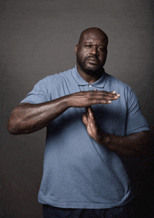 a man in a blue shirt is making a stop gesture