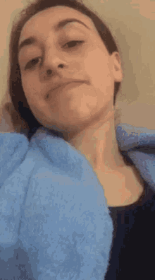 a woman is laying on a bed with a blue towel around her neck and making a funny face .
