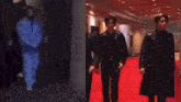 a man in a blue shirt and a man in a black coat are standing on a red carpet .