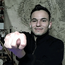 a young man is pointing at the camera with his fist .