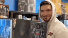 a man in a white hoodie holds a batman action figure in his hands