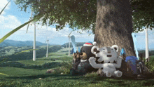 two stuffed animals are sitting under a tree in a field with windmills in the background