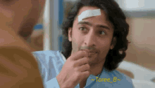 a man with a bandage on his forehead looks at another man with a bandage on his head
