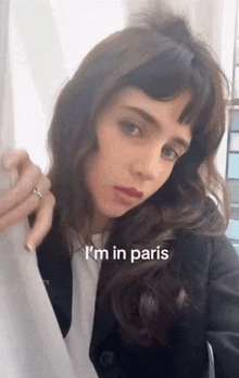 a woman is standing in front of a window and says i 'm in paris .