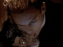 a man is smoking a cigarette while drinking from a glass .