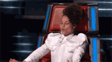 a woman in a white shirt is sitting in a chair with her mouth open