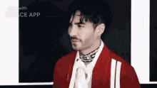 a man wearing a red jacket and a white shirt with a choker around his neck