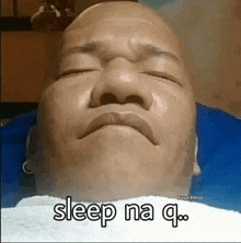 a bald man is laying on a bed with his eyes closed and the words sleep na q .