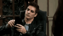 a man is sitting in a chair looking at his cell phone