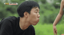 a man in a black shirt is making a funny face while looking at a little girl .