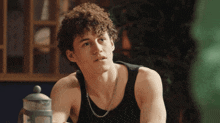 a man with curly hair is wearing a black tank top