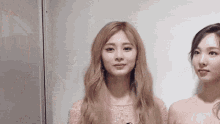 two women are standing next to each other and looking at the camera . one of the women has blonde hair and the other has brown hair .