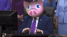 a man wearing a pig mask is typing on a computer keyboard