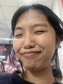 a woman making a funny face with her eyes closed in front of a wall with a picture of a city on it