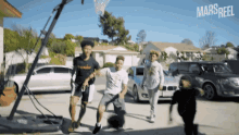 a group of young men are playing basketball in a driveway with cars parked in front of them and the words mars reel on the bottom right
