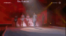 a woman is walking down a runway at a mega tv show