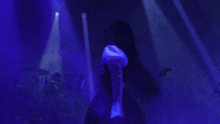 a silhouette of a woman playing a guitar in a dark room