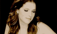 a woman with long hair is smiling and looking down