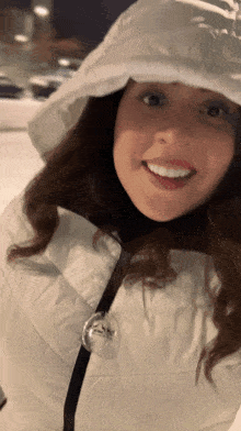 a woman wearing a white jacket with a hood smiles