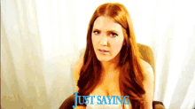 a woman with red hair is sitting in a chair with the words just saying above her