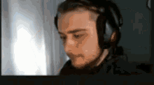 a man with a beard is wearing headphones and looking at a computer screen .