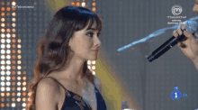 a woman in a black dress is being interviewed by a man holding a microphone .