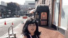 a woman stands on a sidewalk in front of a building that says laugh factory diego