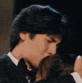 a man in a tuxedo kisses a woman on the forehead