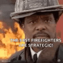 a man wearing a firefighter 's hat is standing in front of a fire .