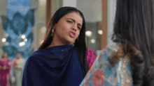 a woman in a blue saree is making a funny face while standing next to another woman in a pink dress .