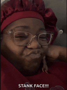 a woman wearing glasses and a red hat with the words stank face written below her