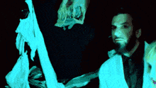 a man with a beard is standing next to a woman in a blue light