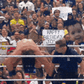 a man in a wrestling ring holding a sign that says happy birthday josh