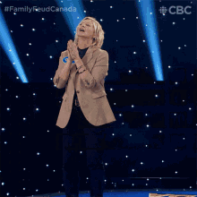 a woman stands on a stage with the words family feud canada on the bottom